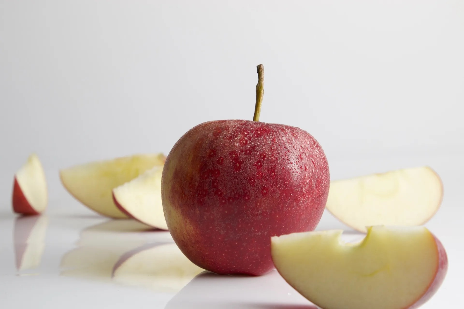 Ganze und geschnittene rote Äpfel auf weißem Hintergrund.